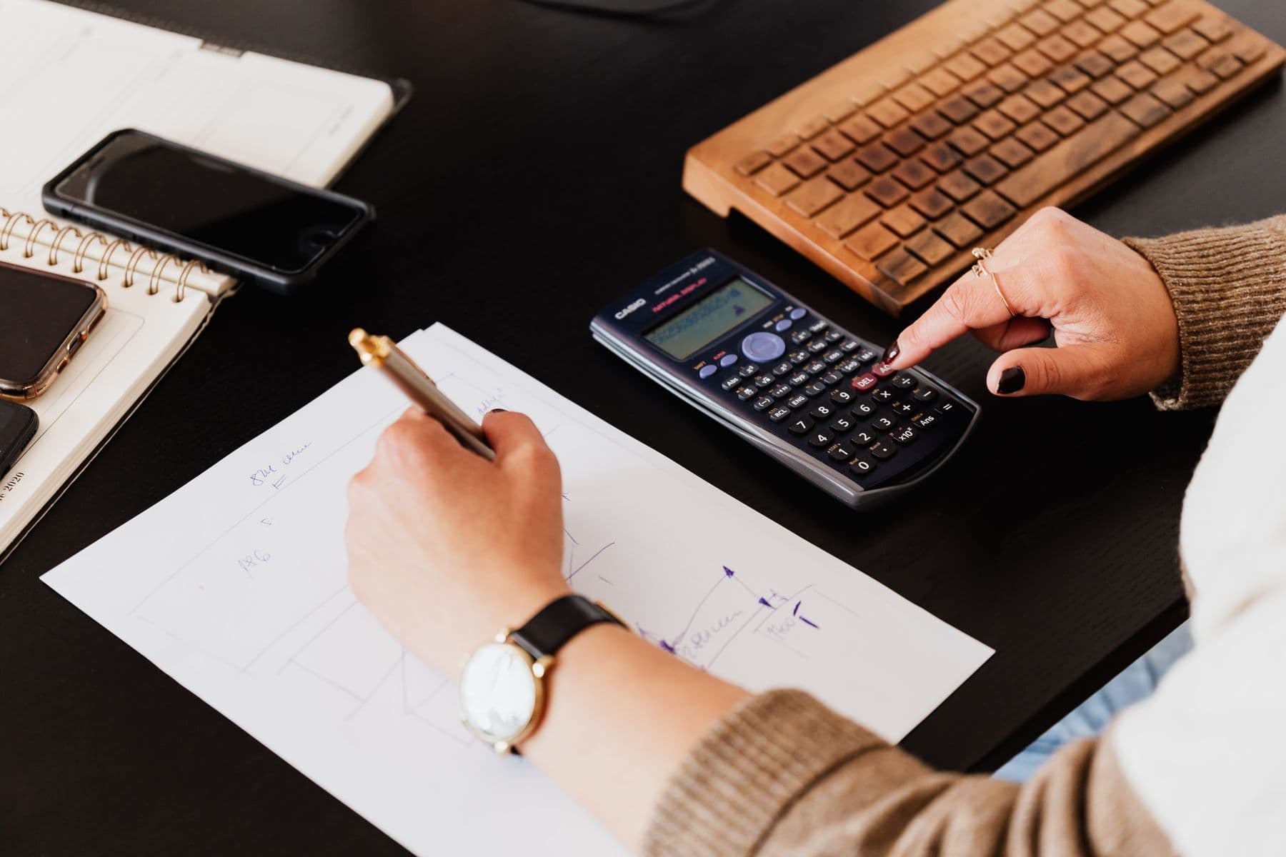 Hands checking financial records with a calculator and notebook