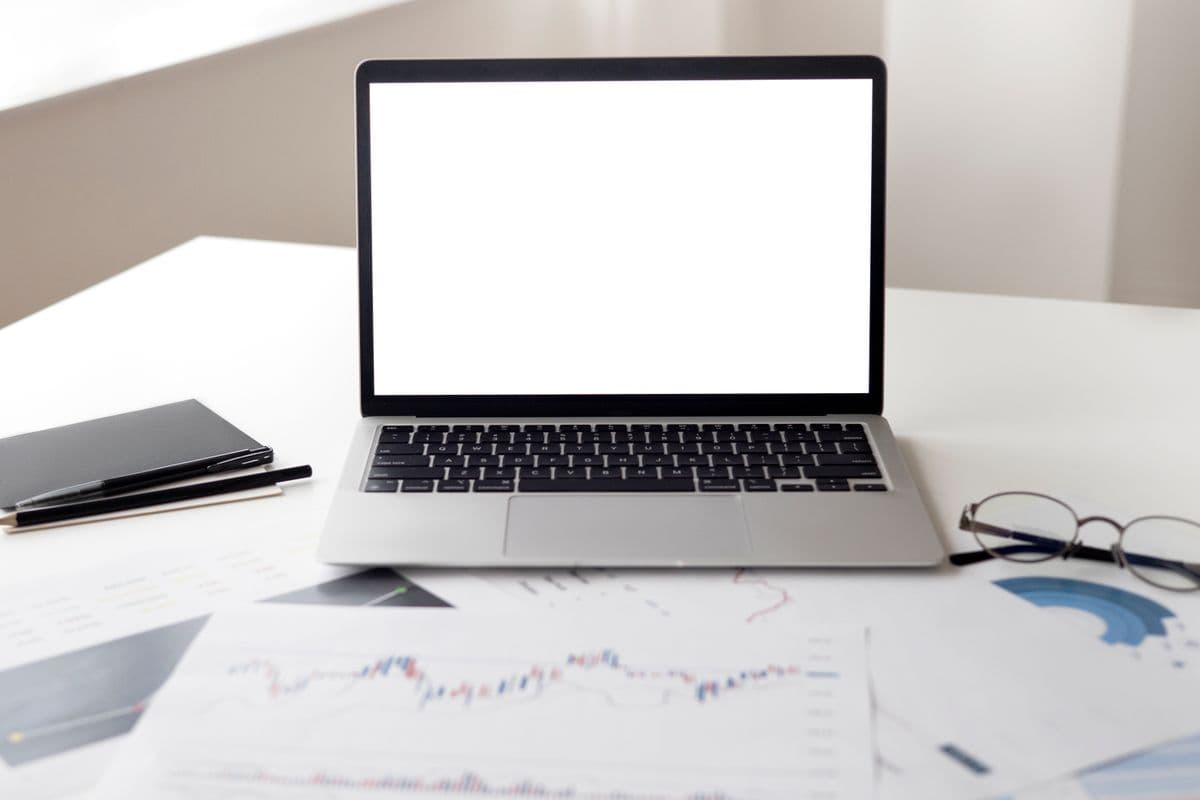 Financial documents and an open laptop on a desk